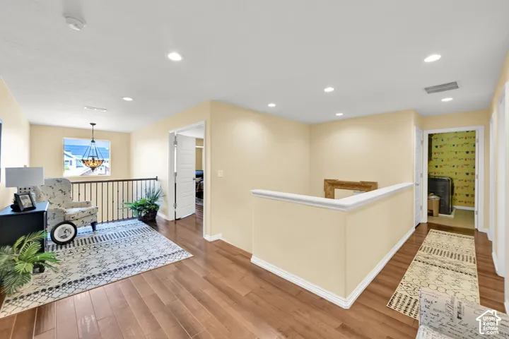Hardwood-style flooring throughout, recessed ceiling lighting, wrought iron baluster railing, and a window with a hanging light fixture