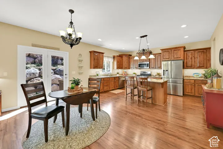 Open-concept kitchen and dining area featuring wood-finish flooring, recessed lighting, wood cabinetry, and stainless steel appliances