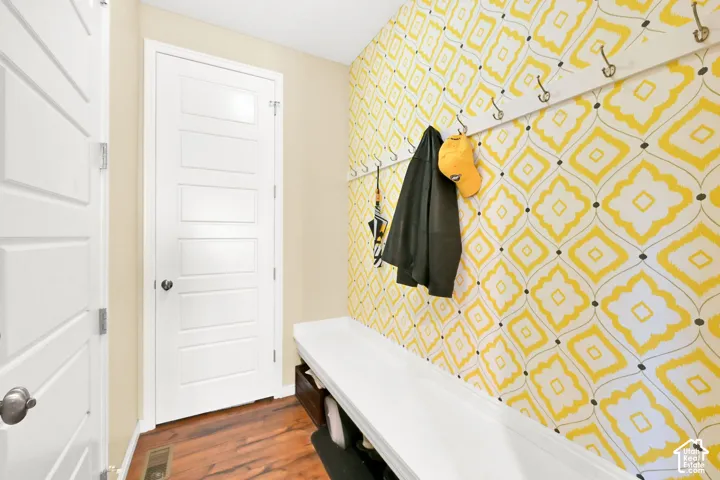 Entryway featuring wood-finish flooring, a white built-in bench, and a wall-mounted coat rack