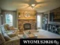 Stone-clad fireplace with mantel, ceiling fan, and window with drapes