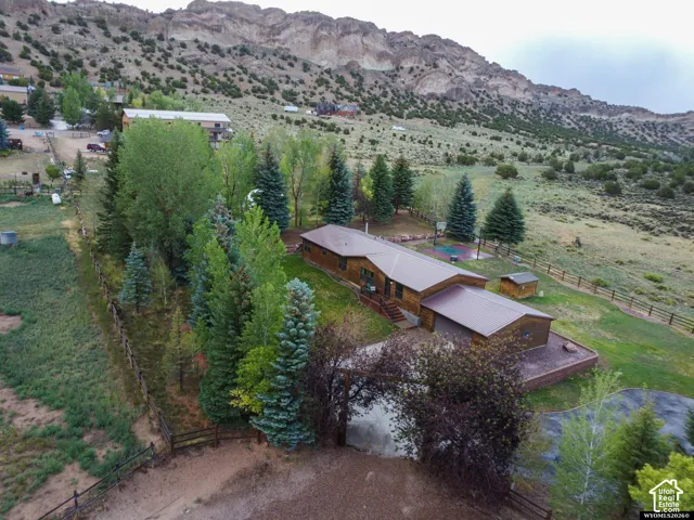 Log-sided residence with a brown metal roof, set on a sloped lot with a natural landscape