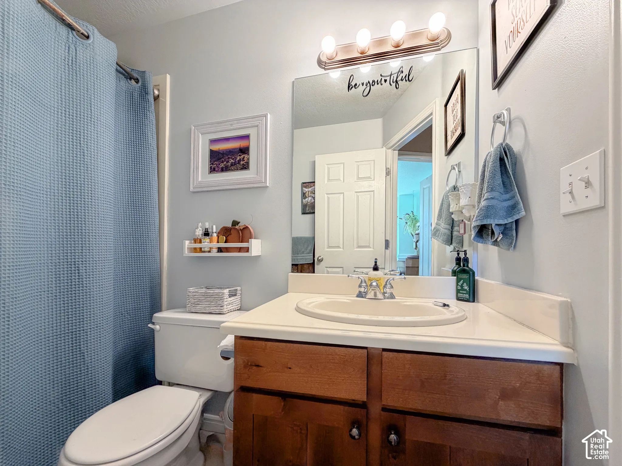 Bathroom featuring a single vanity with wood-finish cabinetry, a single basin sink, and an integrated countertop