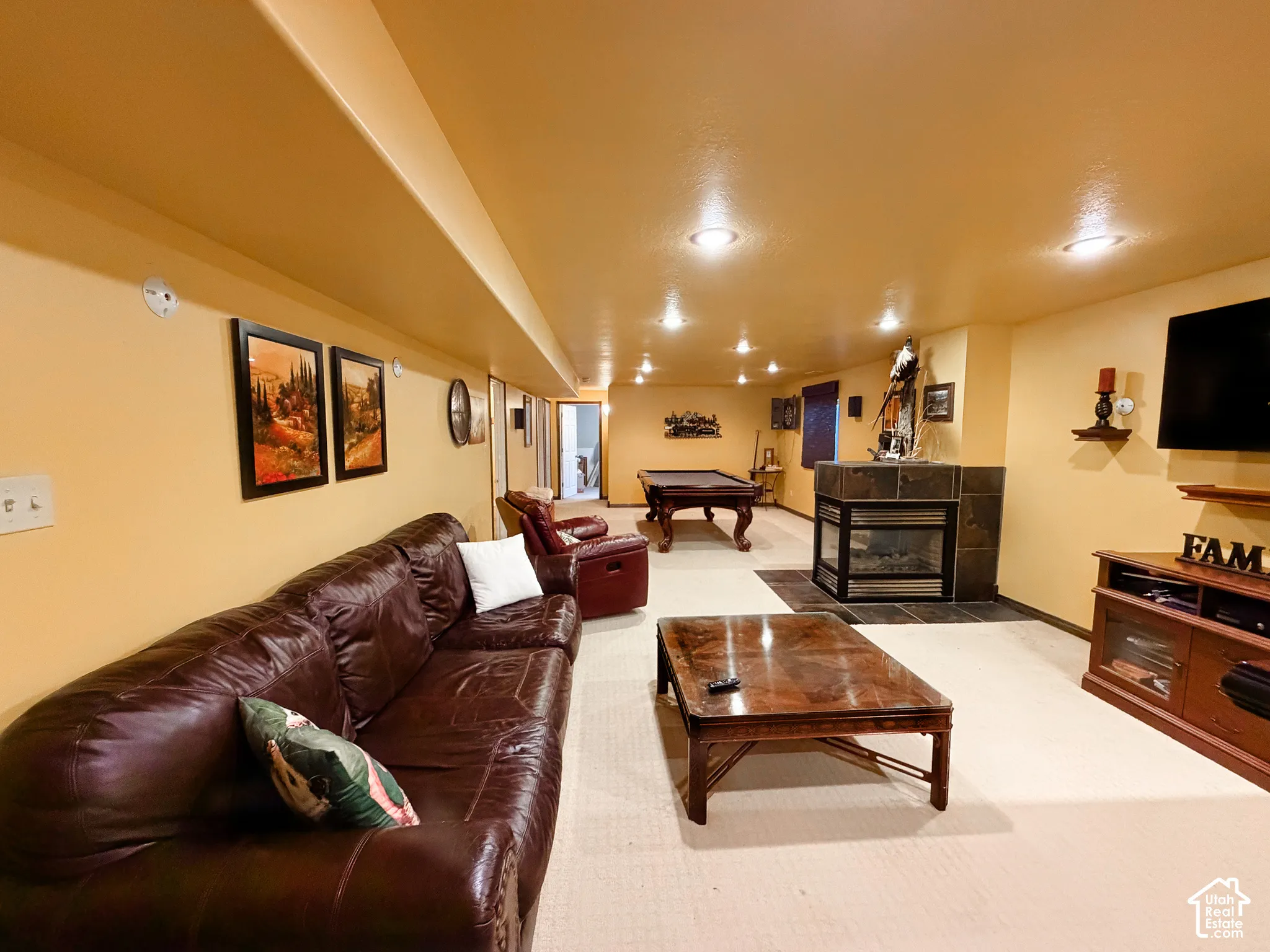 Spacious recreation room featuring recessed lighting, a built-in fireplace with a tile surround, and carpet flooring