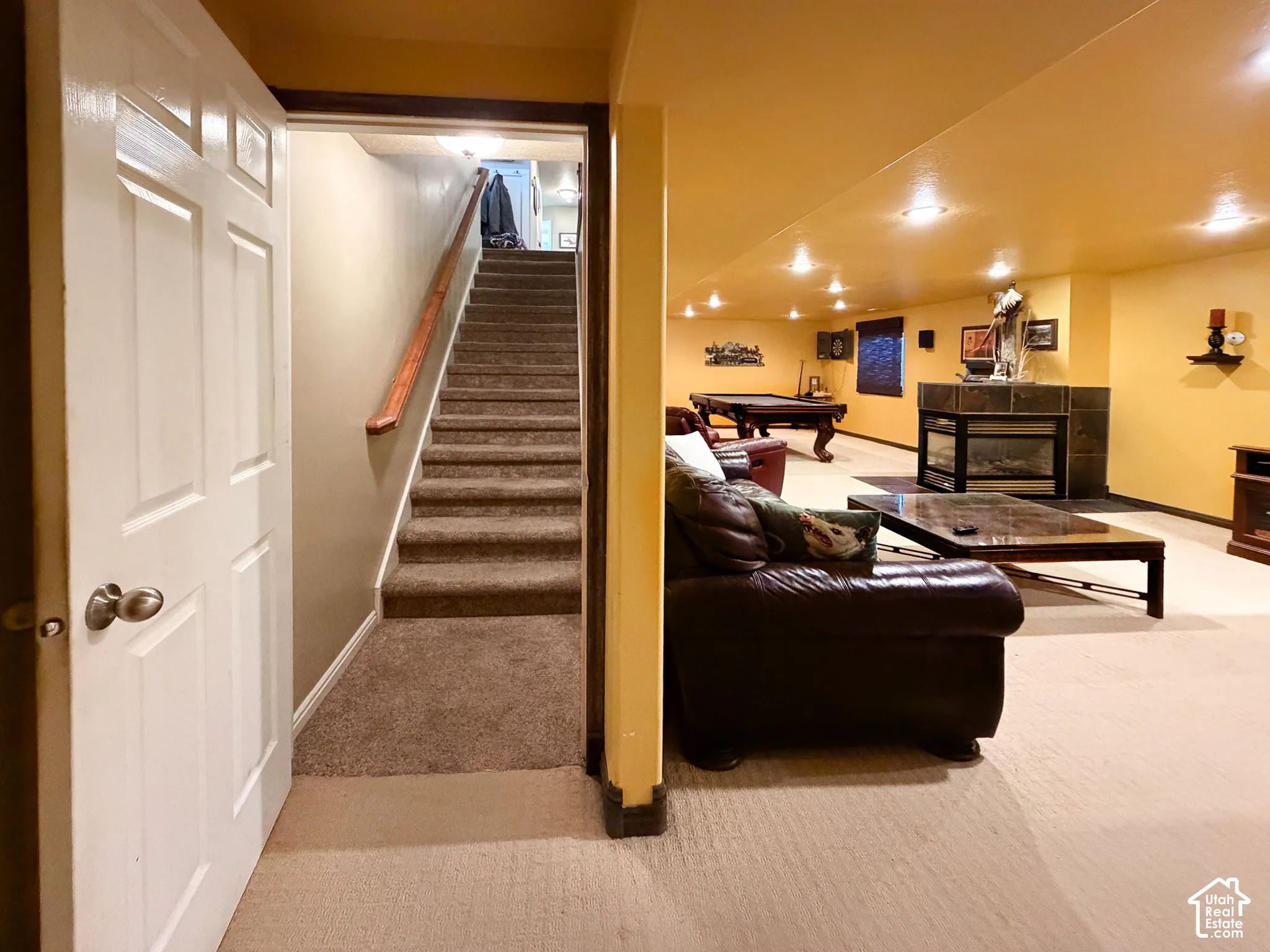 Finished lower level with recessed lighting, carpet flooring, a stone-clad fireplace, and a built-in entertainment area