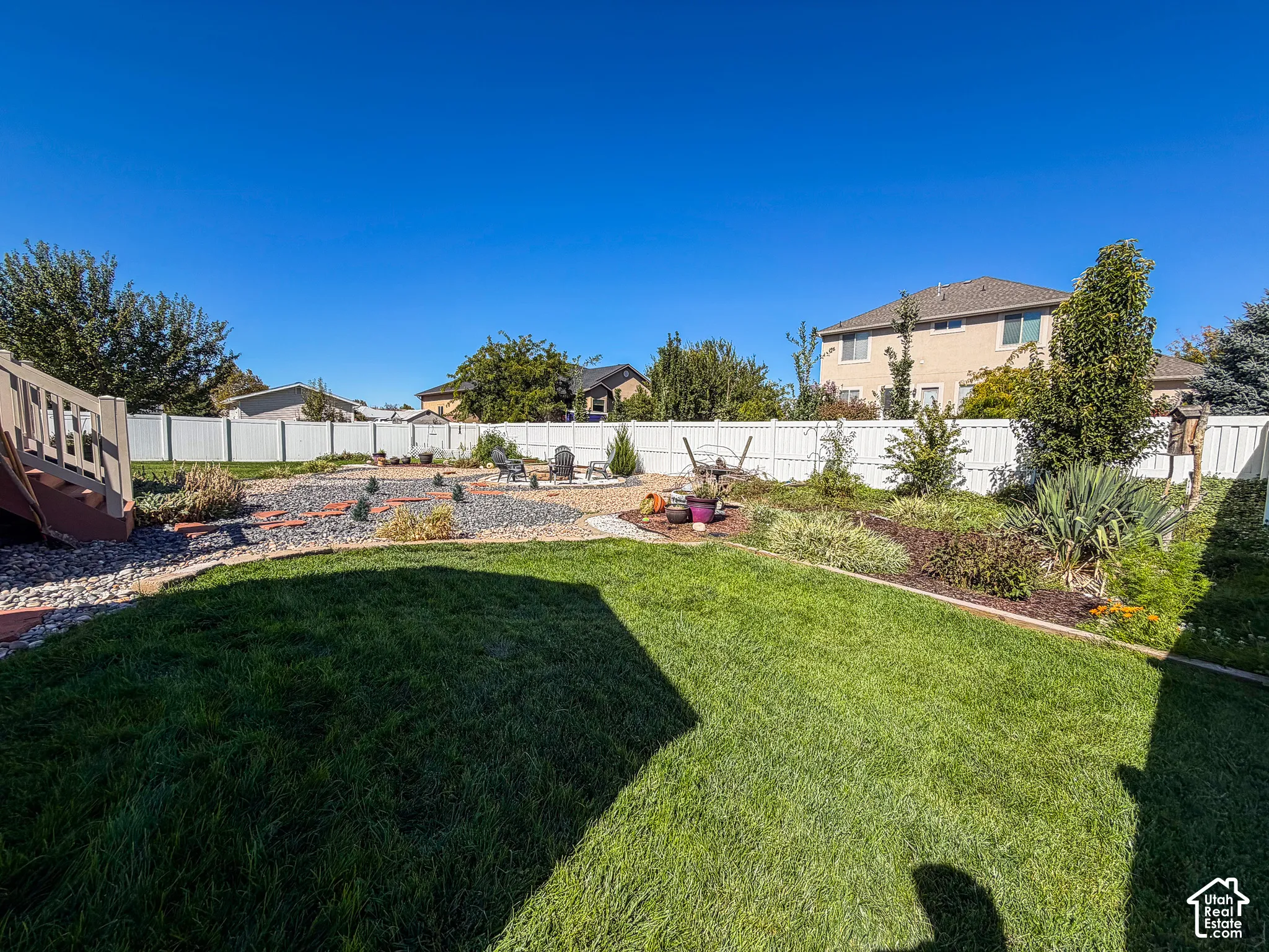 Expansive backyard featuring a manicured lawn, established landscaping, and a privacy fence