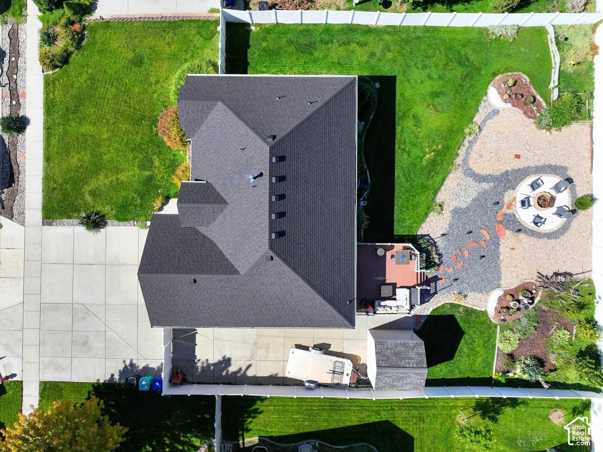 Manicured lawn, concrete driveway, multi-level decking, gravel and stone patio, and a privacy fence