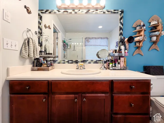 Vanity with a white countertop and integrated sink, framed mirror with mosaic tile detailing, and a multi-bulb light fixture