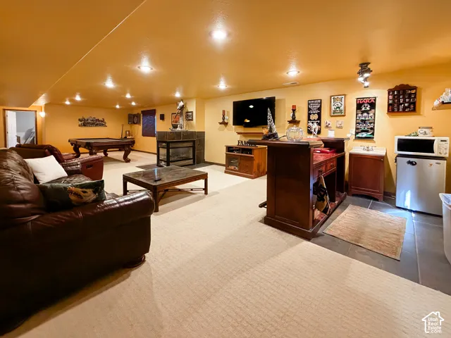 Recessed lighting illuminates carpeted flooring and a built-in fireplace with a stone surround