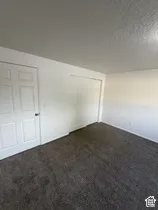 Textured ceiling, wall-to-wall carpeting, and white paneled doors