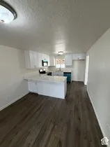 Kitchen featuring white cabinetry, light-toned countertops, wood-finish flooring, and a breakfast bar