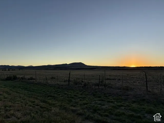 Expansive open field with distant mountain range, featuring a clear sky and natural vegetation