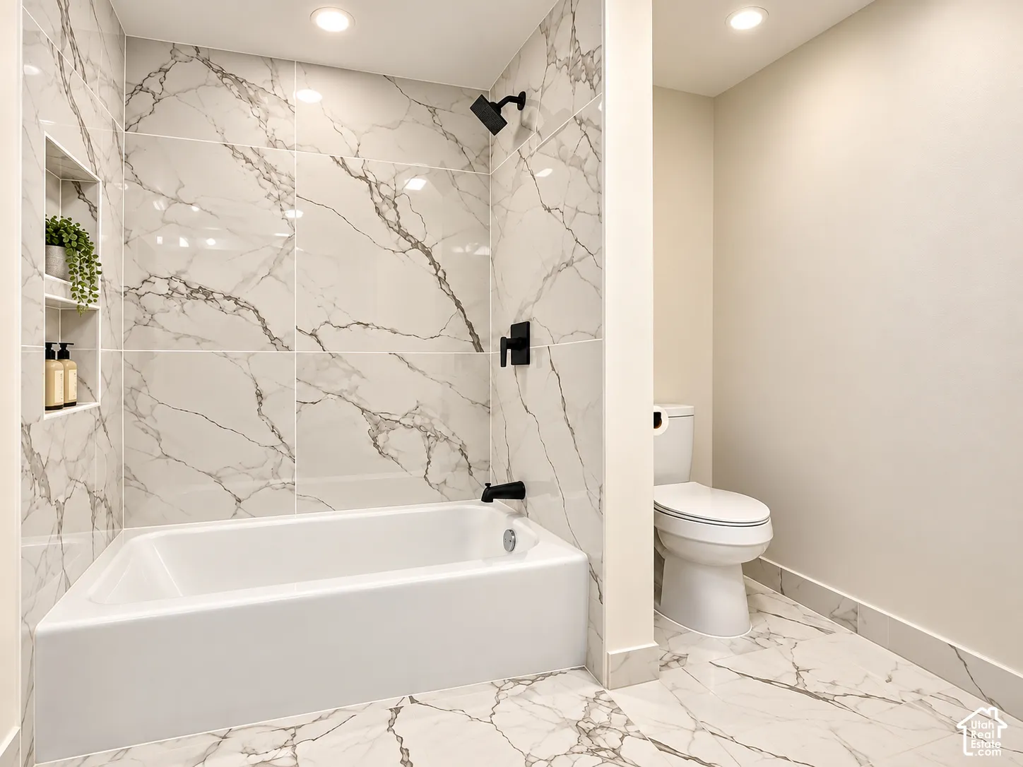 Built-in bathtub with a tile surround, recessed shower niche, and matte black fixtures