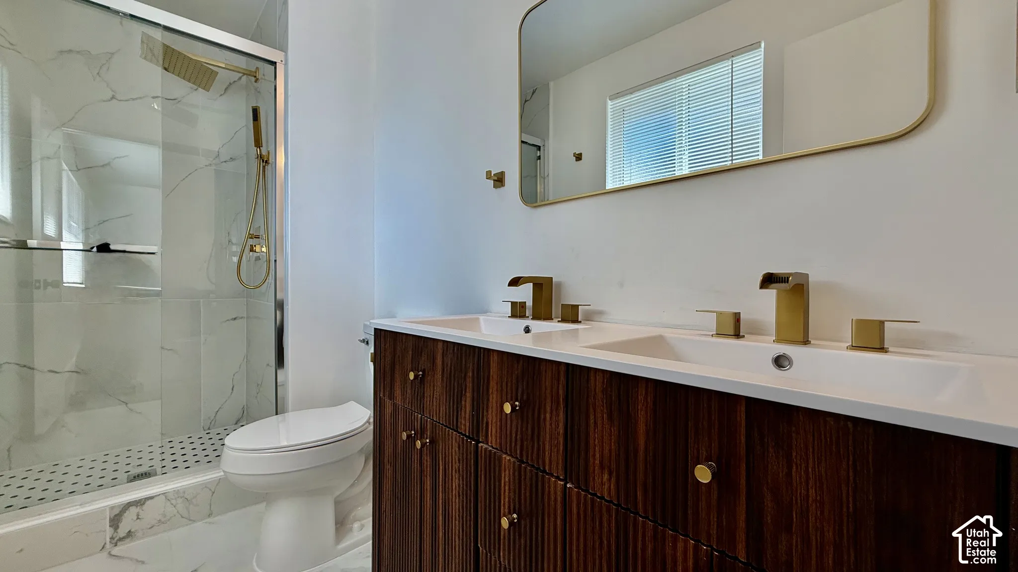 Dual vanity with integrated sinks, brushed gold fixtures, and a wood-finish cabinet