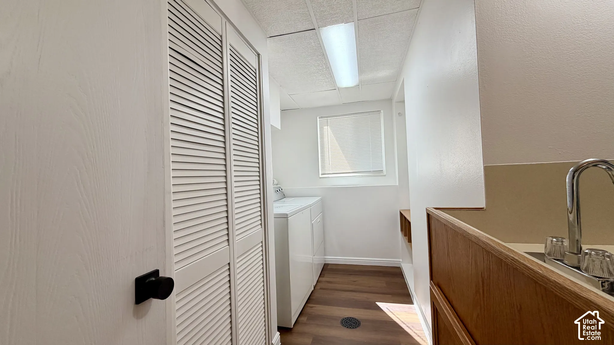 Utility area featuring a built-in sink with a chrome faucet, wood-finish cabinetry, and wood-finish flooring