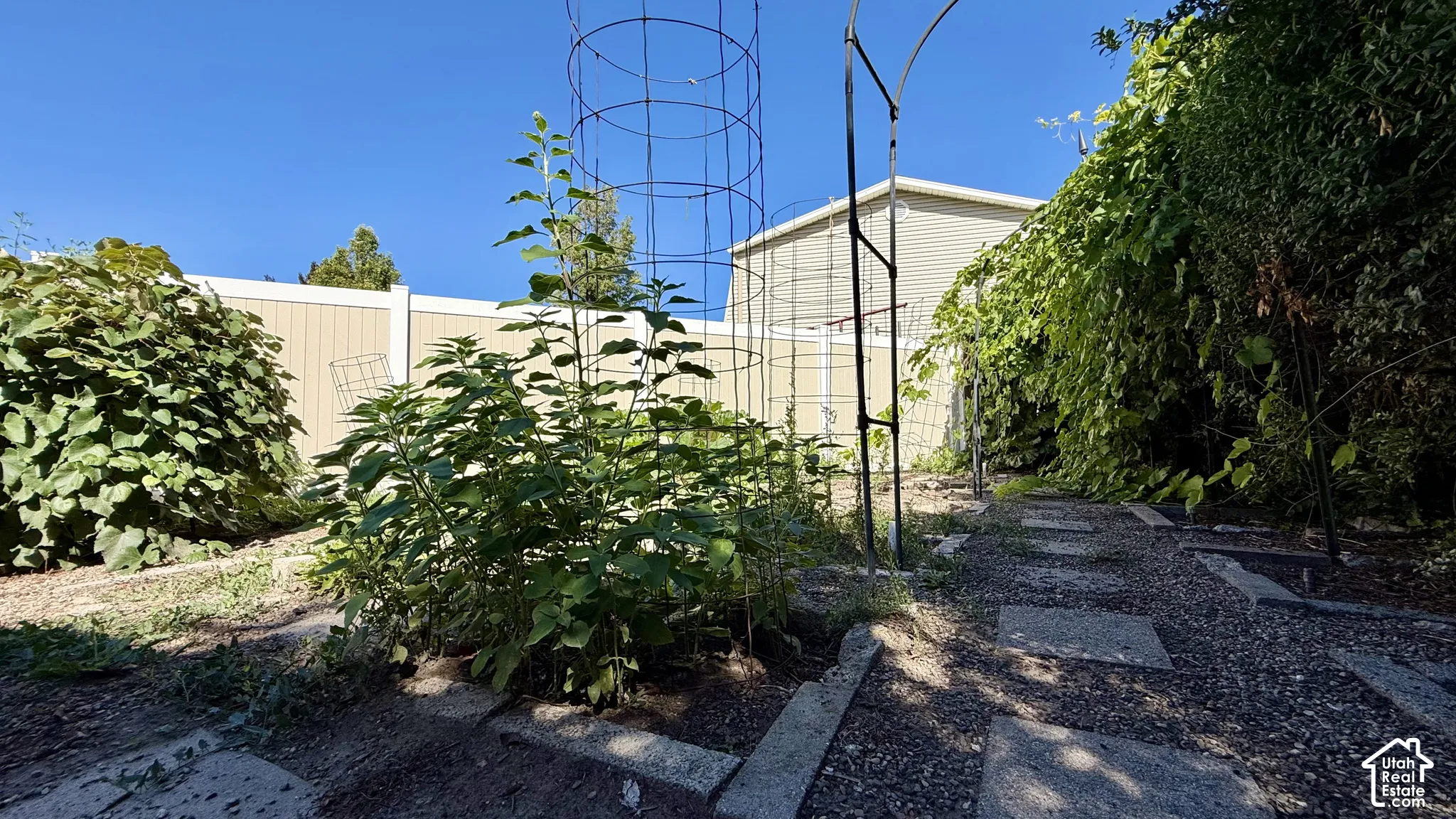 Garden area featuring a gravel path with stone pavers, established plantings, and a privacy fence