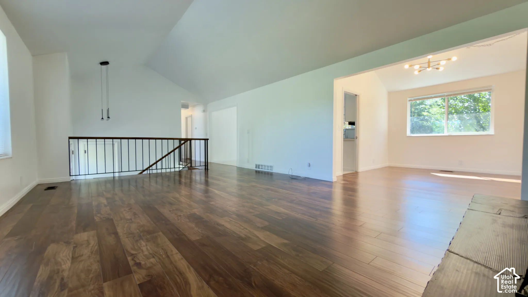Vaulted ceiling with a contemporary pendant fixture, wood-finish flooring, and an open concept layout