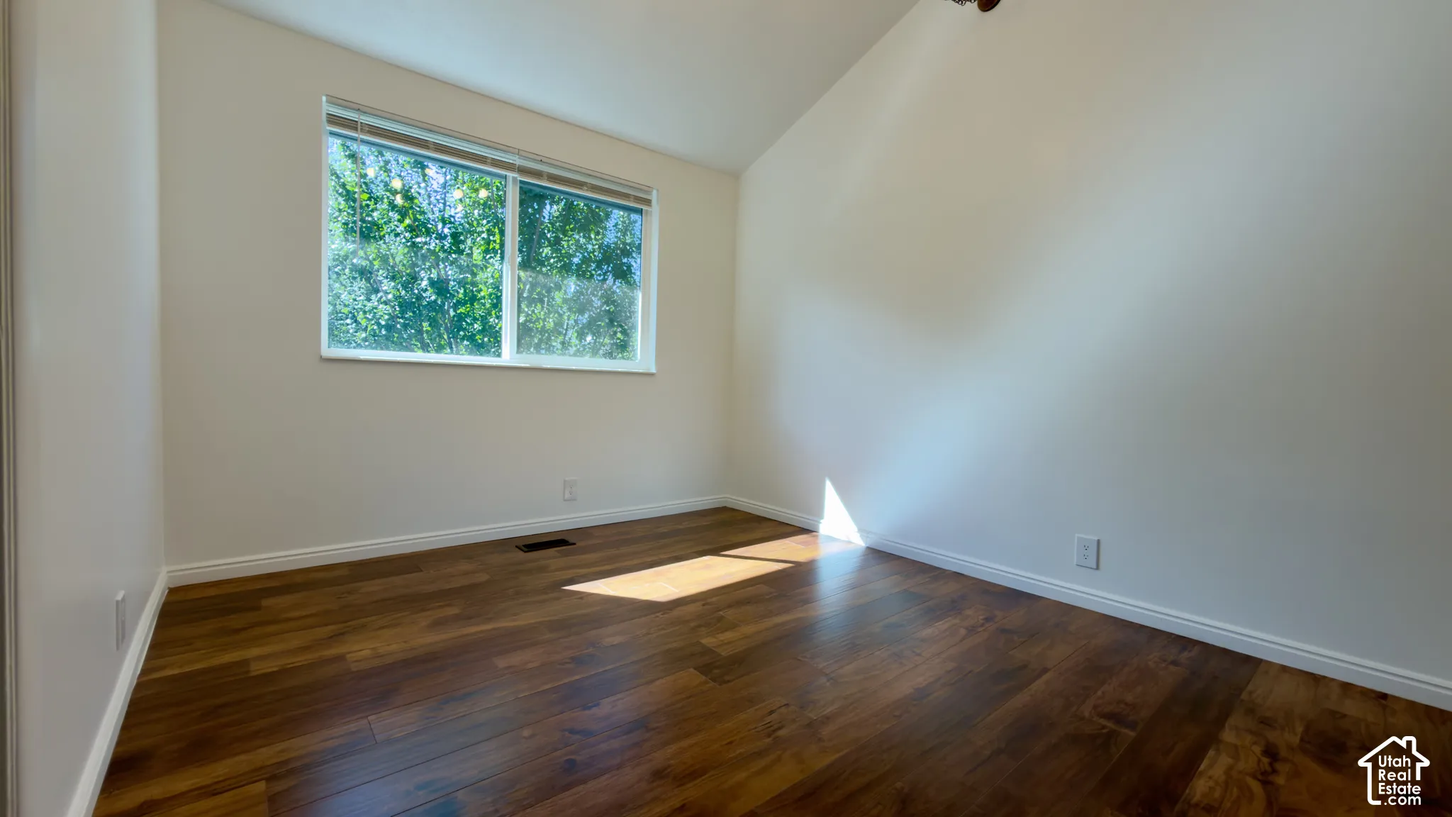 Wood-finish flooring with white baseboards, a large window, and a ceiling-mounted light fixture