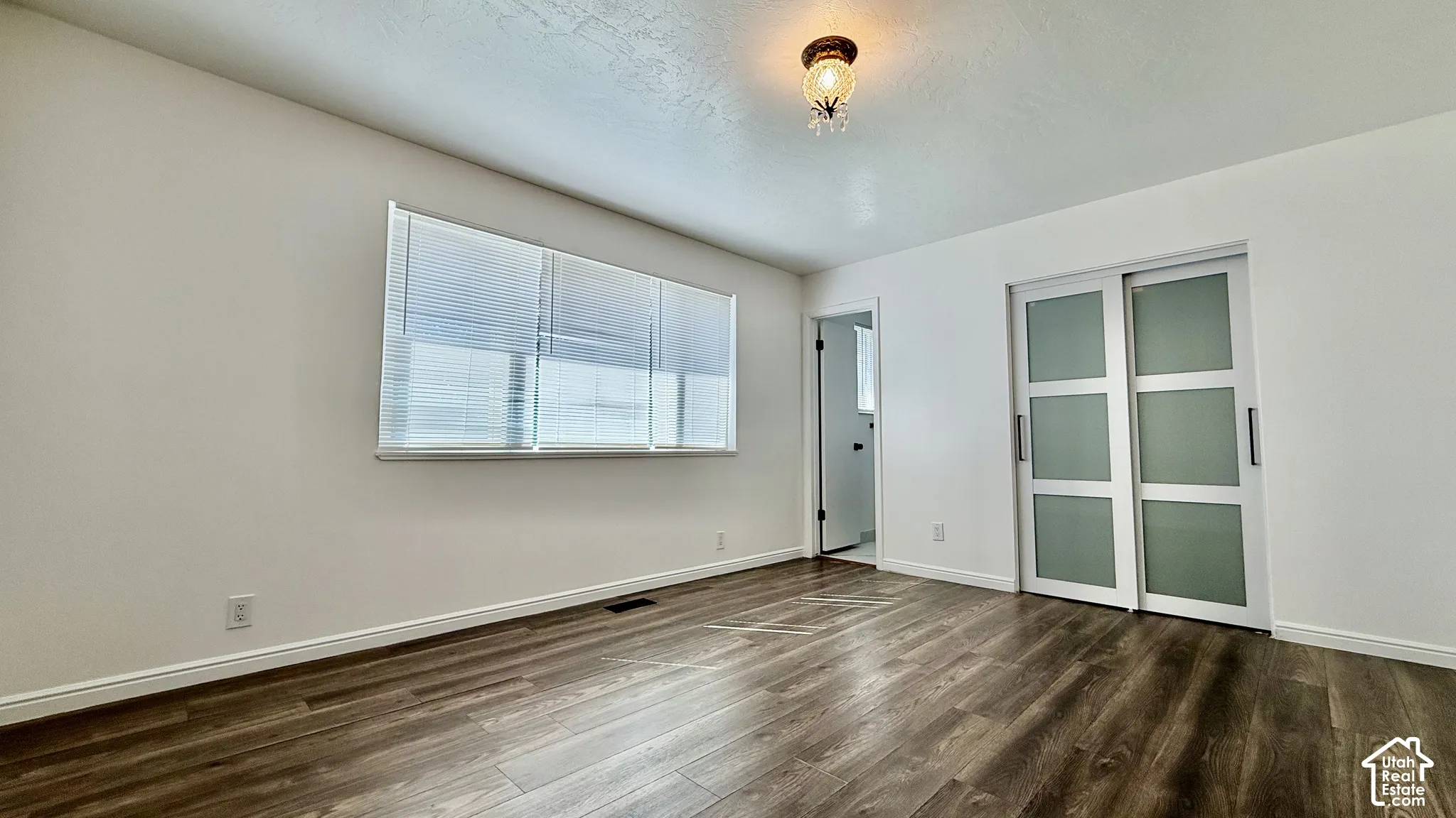 Wood-finish flooring, white walls, and a window with blinds