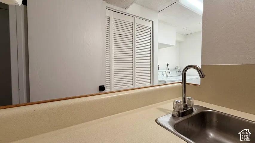 Utility sink with chrome faucet set into a light-toned countertop, featuring an adjacent louvered bifold door