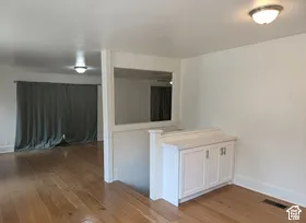 Hardwood flooring throughout, white baseboards, and built-in white cabinetry with a light-toned countertop
