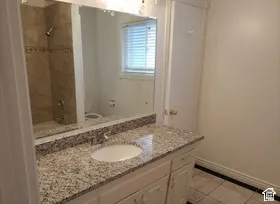 Bathroom featuring a vanity with an integrated sink, a speckled countertop, and white cabinetry