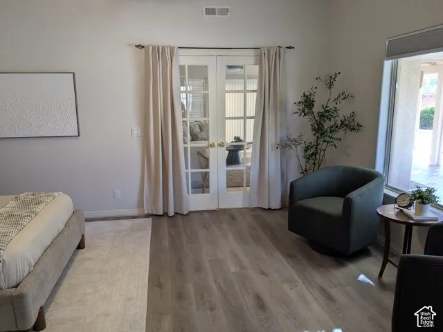 Wood-finish flooring throughout, French doors with louvered blinds, and recessed lighting