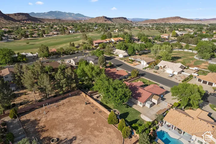 Residential neighborhood with mature trees, surrounded by arid mountains, and featuring a golf course
