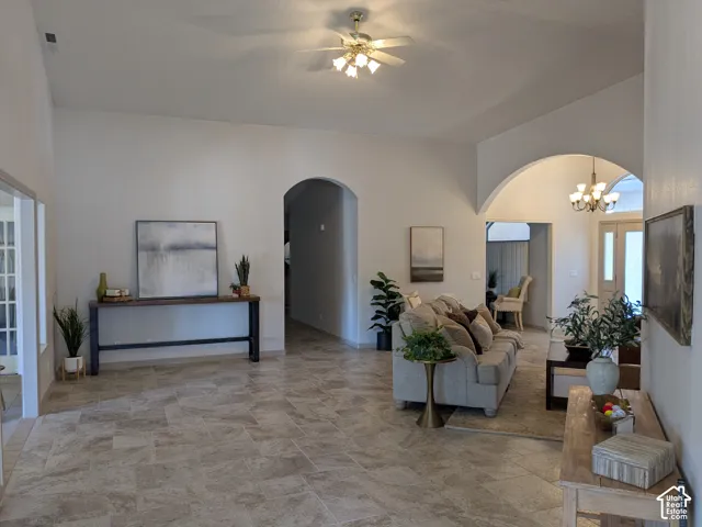 Vaulted ceilings, arched doorways, tiled flooring, ceiling fan with light fixture, and recessed lighting
