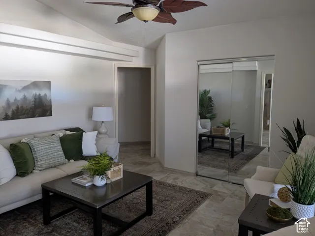 Vaulted ceiling with exposed beams, ceiling fan light fixture, tile flooring, and mirrored closet doors