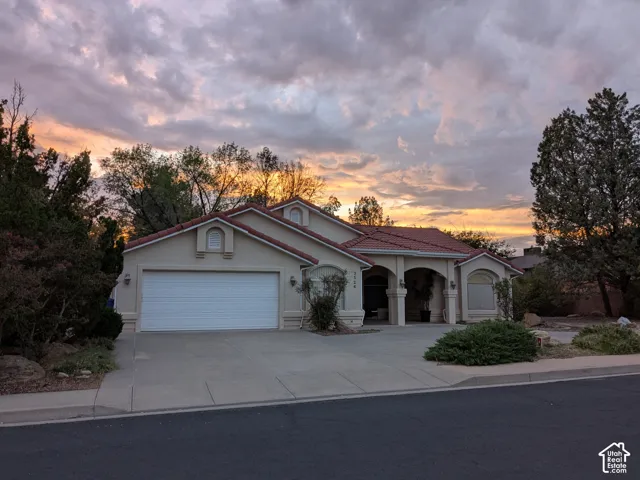 Stucco exterior with a tile roof, an integrated garage, and a paved driveway