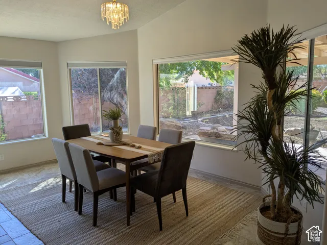 Recessed dining area with multiple windows, vaulted ceiling, and an ornate crystal chandelier