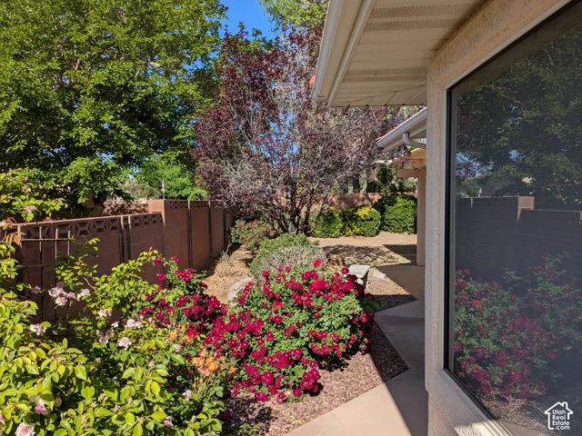 Landscaped side yard featuring a variety of flowering shrubs, mature trees, and a decorative block privacy fence