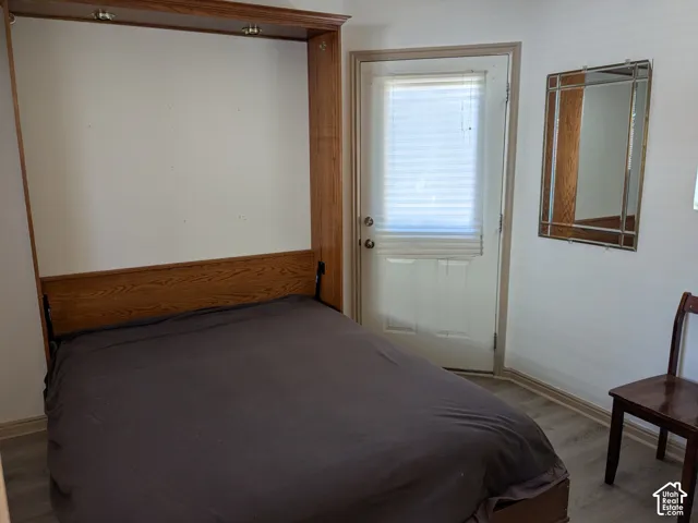 Built-in wood-finish wall bed with integrated lighting, a white door with blinds, and wood-finish flooring