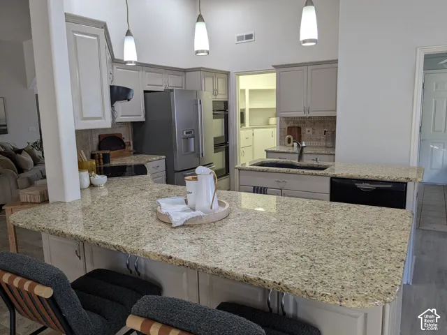 Kitchen featuring granite countertops, shaker-style cabinetry, a built-in double oven, and pendant lighting