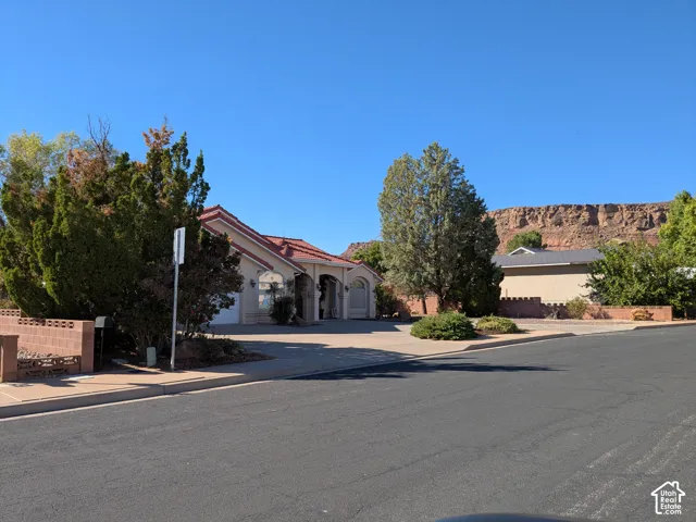 Stucco exterior with a terracotta-style tile roof, mature landscaping, and a paved driveway