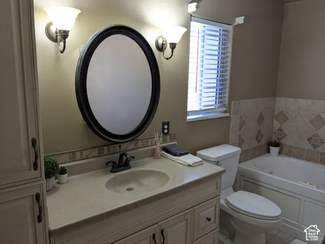 Single vanity with integrated sink, dual wall sconces, oval mirror, and tiled bathtub surround