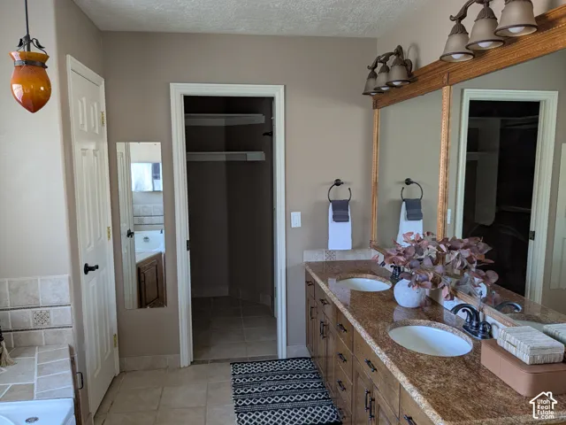 Dual vanity featuring an integrated sink, polished countertop, and decorative mirror