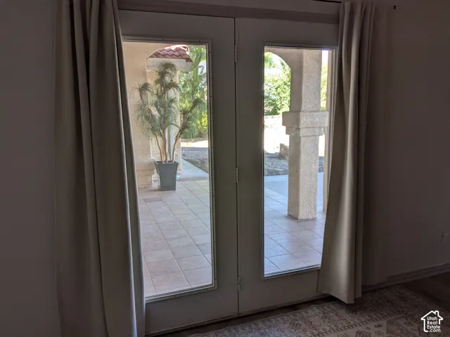French doors opening to a tiled patio with structural columns