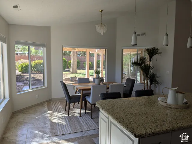 Tiled flooring extending into a dining area with multiple windows, a chandelier, and a sliding glass door