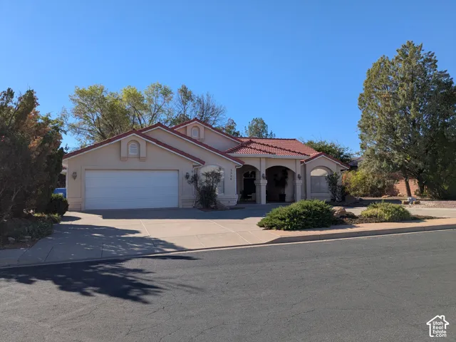 Stucco exterior with a red tile roof, arched entryways, and an attached two-car garage