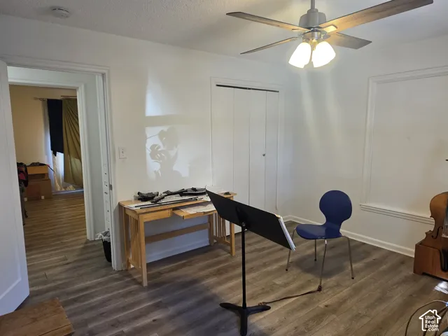 Wood-finish flooring throughout, white painted walls, and a ceiling fan with integrated lighting