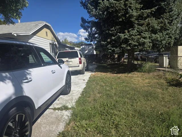 Siding exterior with a gable roofline, mature trees, and a concrete driveway