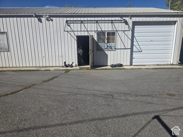 Corrugated metal siding, metal roof, overhead door, and entry door with awning