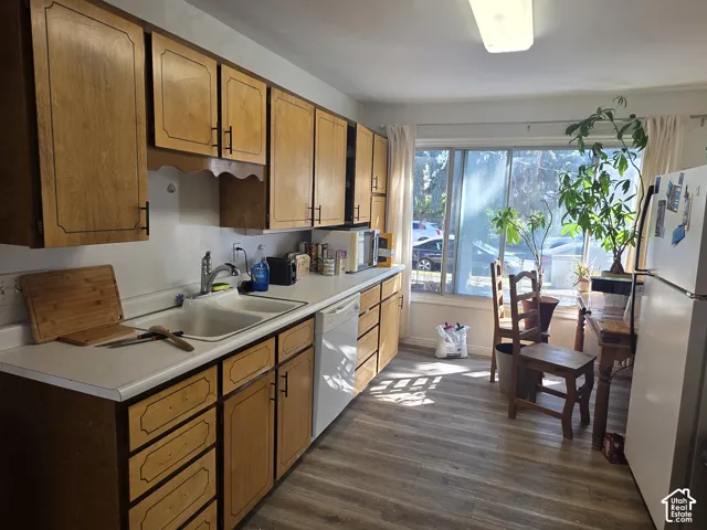 Kitchen featuring wood-finish cabinetry, white countertops, a double-basin sink, and wood-finish flooring