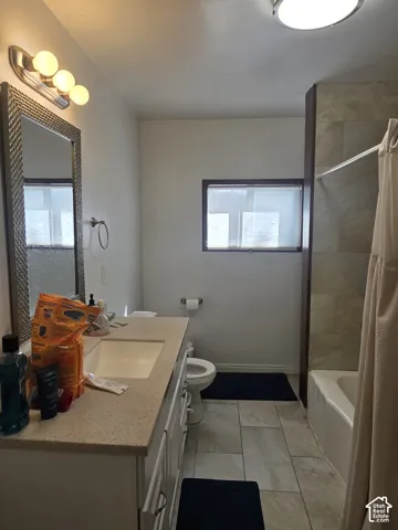 Bathroom featuring a vanity with an integrated sink, a large framed mirror, a built-in bathtub, and tile flooring