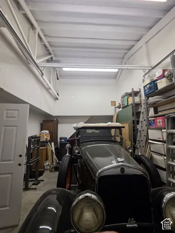 Spacious interior garage with exposed beam ceiling, white walls, and fluorescent lighting