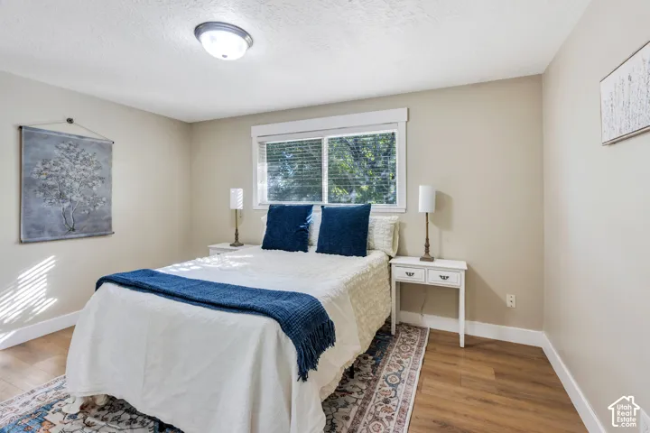 Recessed window with blinds, wood-finish flooring, ceiling-mounted light fixture, light-toned wall paint, and white trim