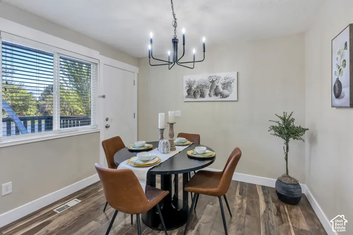 Wood-finish flooring, a contemporary black chandelier, neutral wall tones, and white trim
