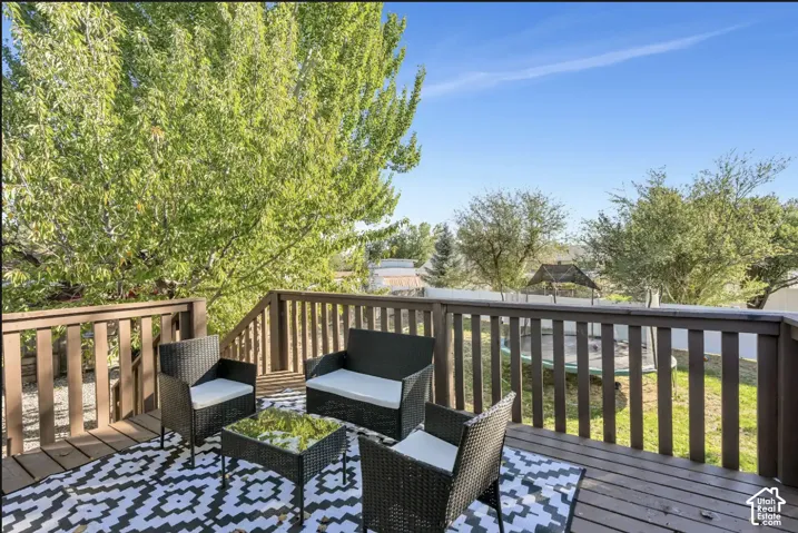 Expansive wooden deck with coordinating railings and steps, featuring a vibrant green tree and a clear blue sky