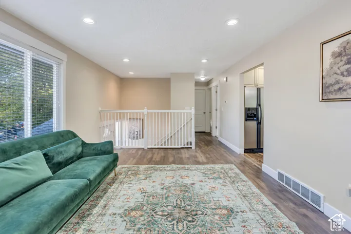 Wood-finish flooring throughout, recessed ceiling lighting, and white baluster railing